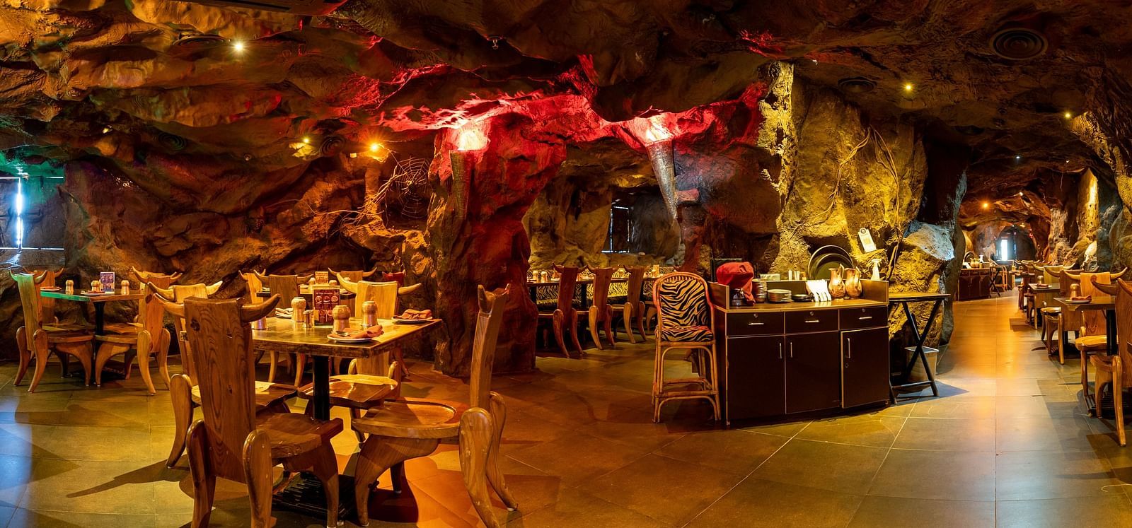 An image of cave themed restaurant with a few sets of chairs and table - The Presidet Hotel, Hubli