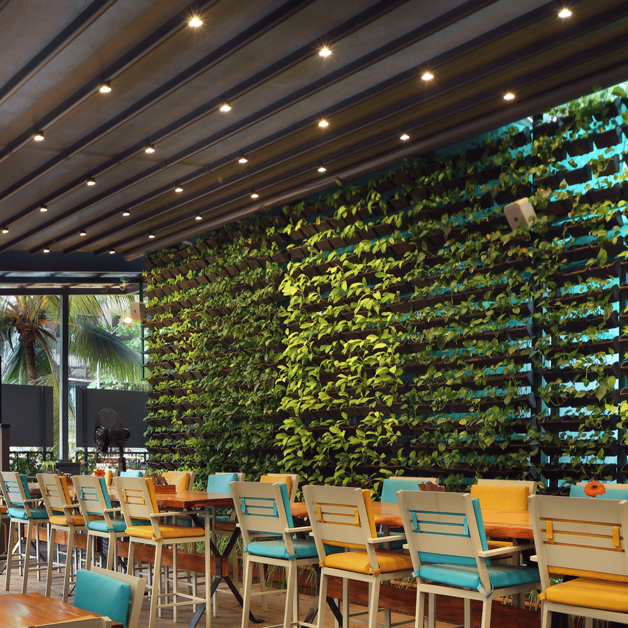 Restaurant dining area with colorful seating and a prominent vertical green plant wall.
