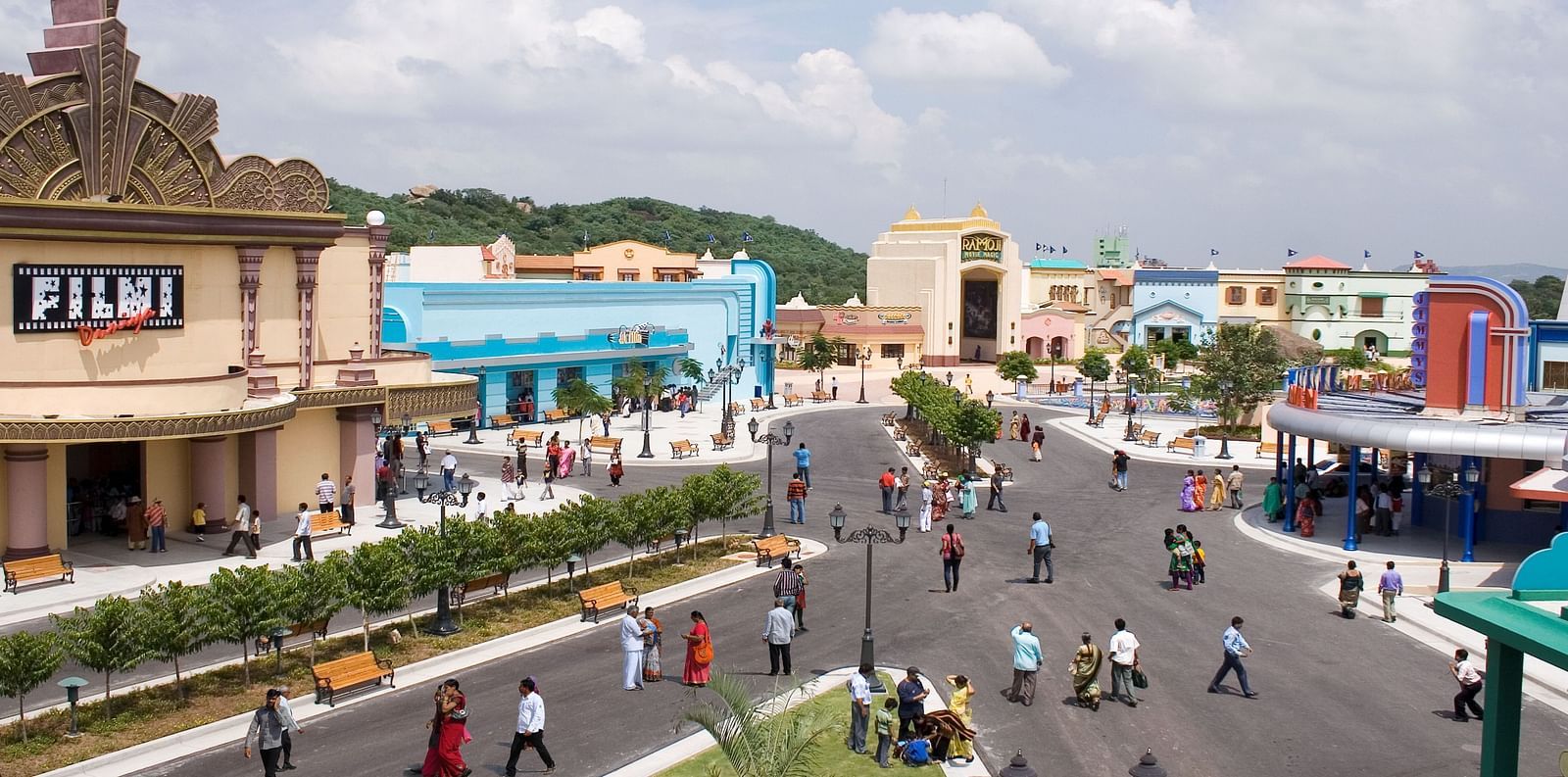 An aerial view of a modern, bustling amusement park with various attractions and themed buildings under a cloudy sky, depicting a lively and family-friendly environment at Ramoji Film City Hotels in Hyderabad 