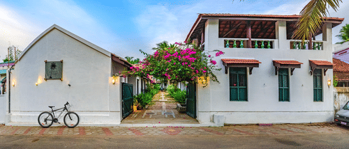 A view of the room cottage exterior with a cycle outside at Neemrana's Coconut Alley - 21st century, Tranquebar, one of the best Tharangambadi hotels.