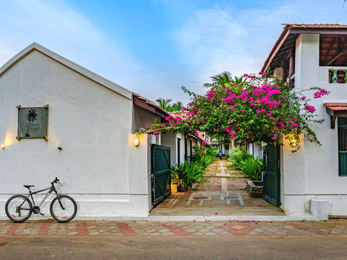 A view of the room cottage exterior with a cycle outside at Neemrana's Coconut Alley - 21st century, Tranquebar, one of the best Tharangambadi hotels.