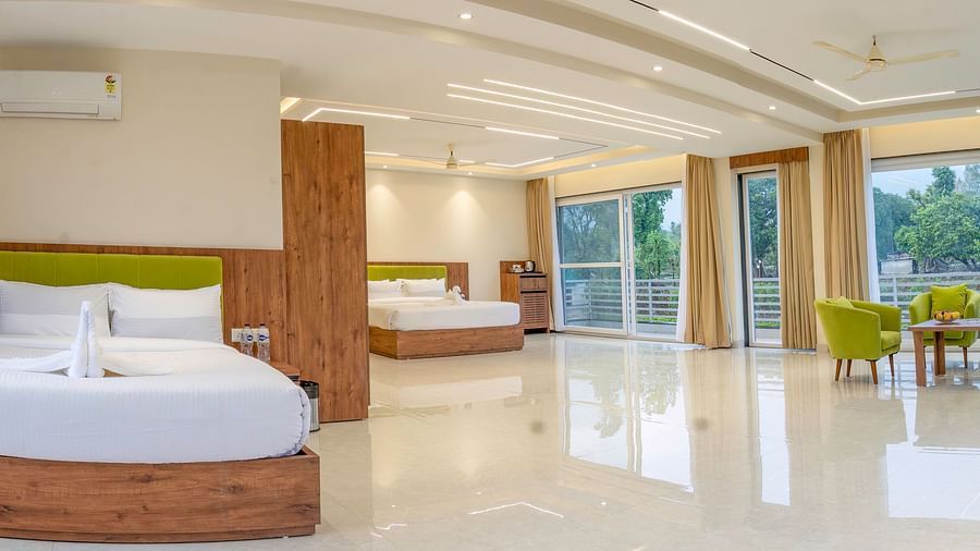 view of the two beds, floor to ceiling windows, and the seating area in the suite at Corbett Four Seasons, Ramnagar