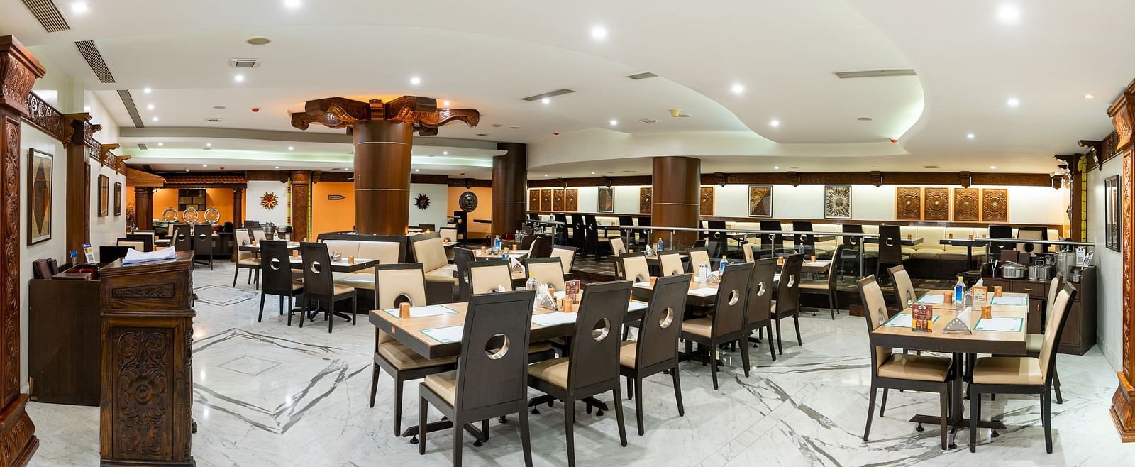 An image of a restaurant with several sets of chairs and table, and at one corner there is a reception desk - Pai Group of Hotels