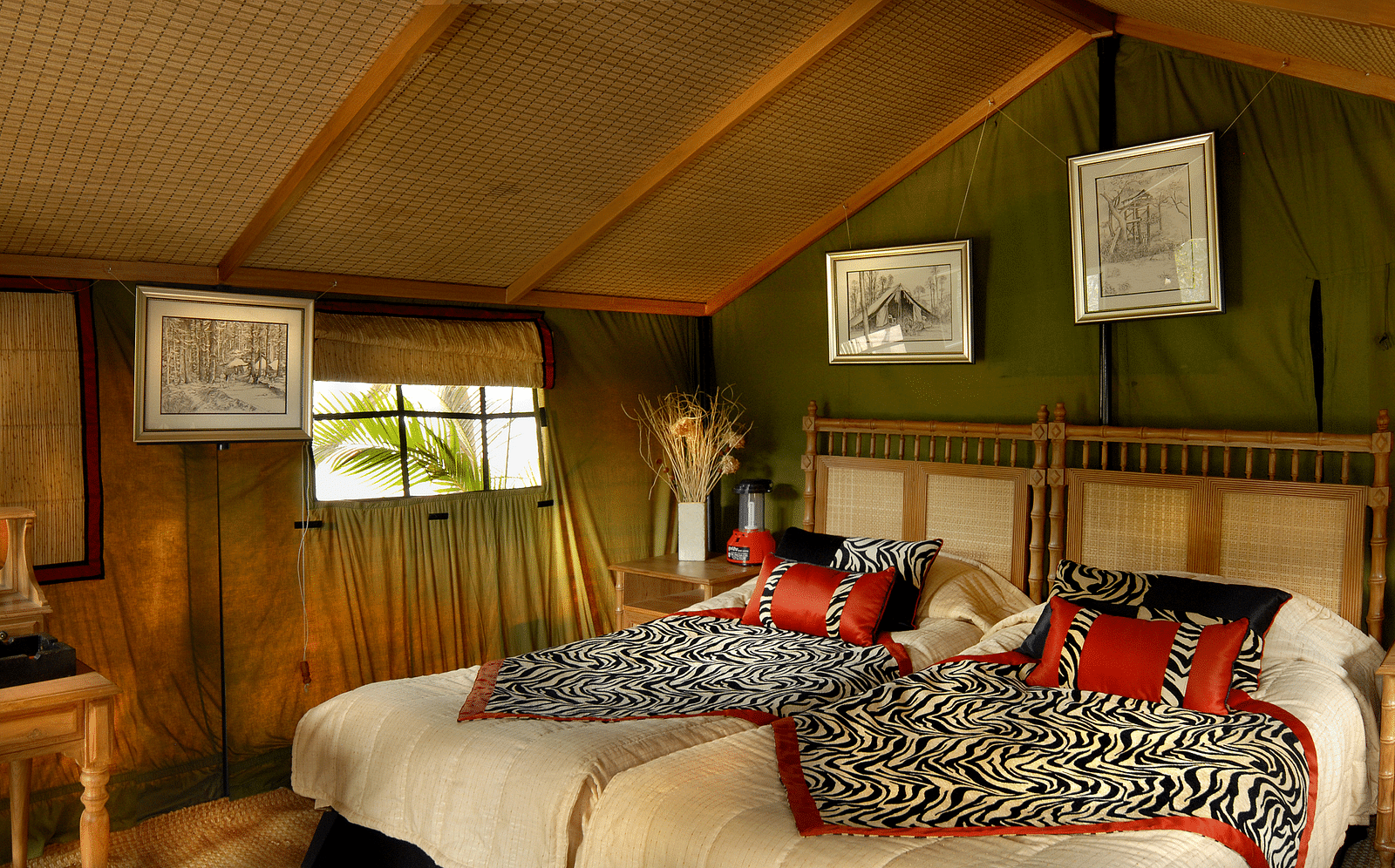 An image featuring a cozy tent in The jamoon corbett, with double bed, coffee table and chairs, along with few photo frames hanging on the either sides.