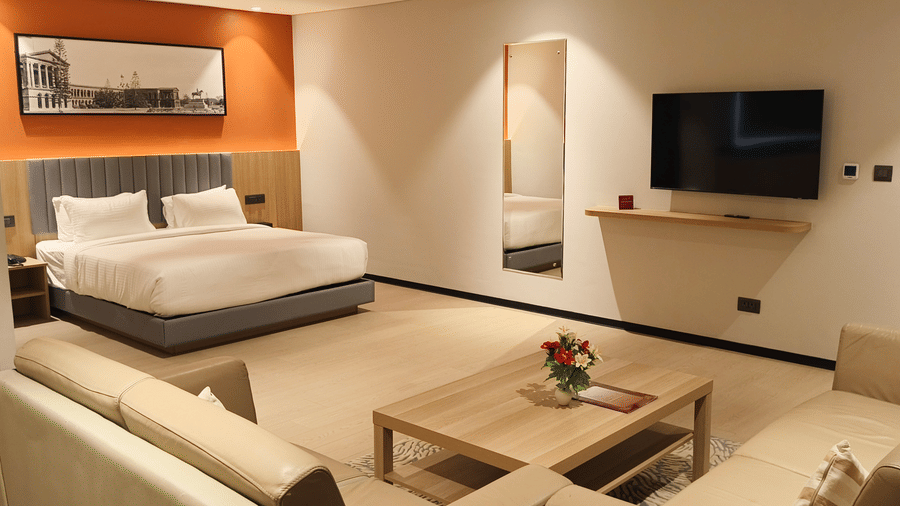 Spacious Suite Room at De Venetian by TGI, Brookefield, Bangalore featuring a king-size bed, seating area, and modern interiors.