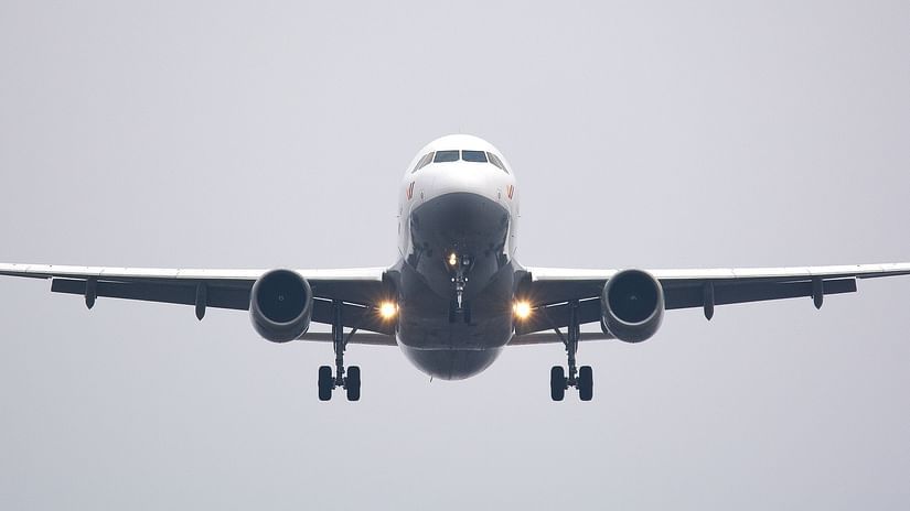 A picture from below showing a plane flying in the air with the landing gear in view.