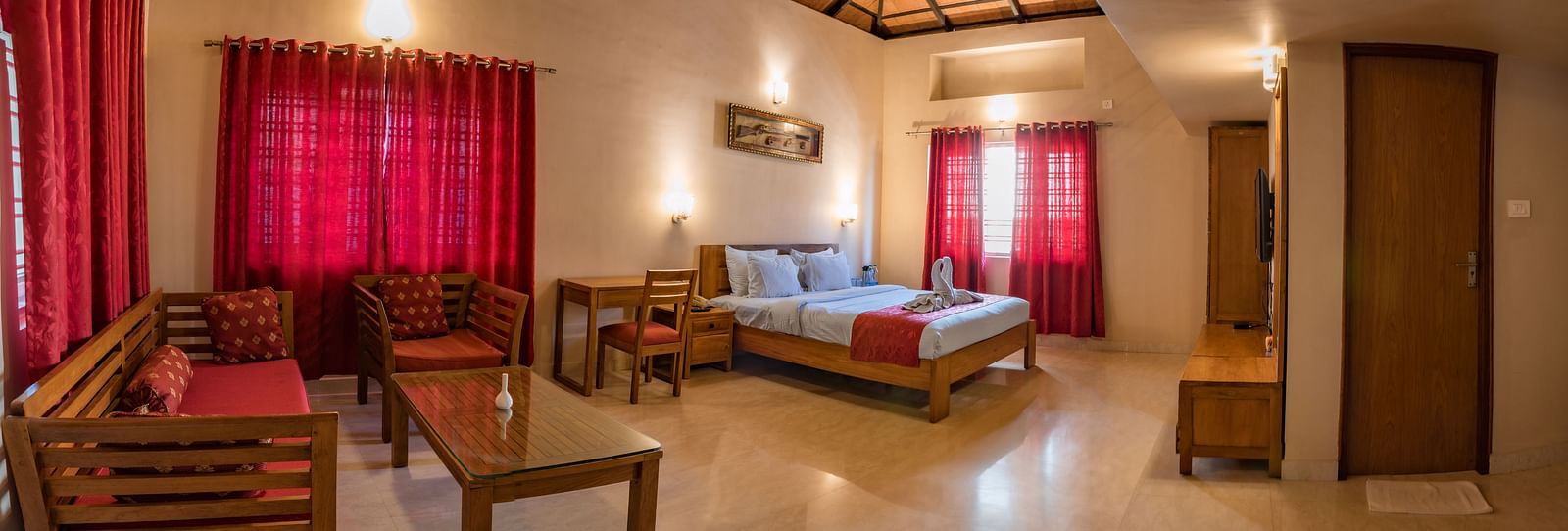 A wide-angle view captures the entirety of Attic Villa, showcasing the bed, seating area, and overall layout | Woodstock Resorts, Coorg