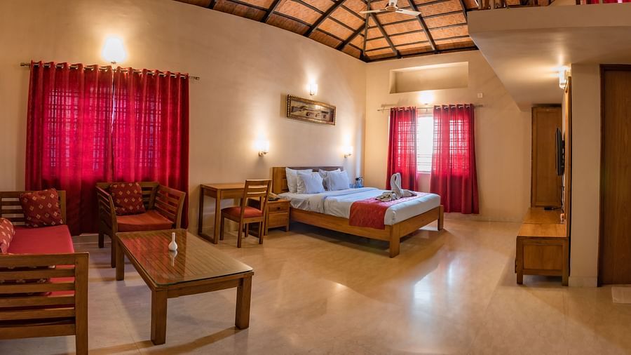 A wide-angle view captures the entirety of Attic Villa, showcasing the bed, seating area, and overall layout | Woodstock Resorts, Coorg