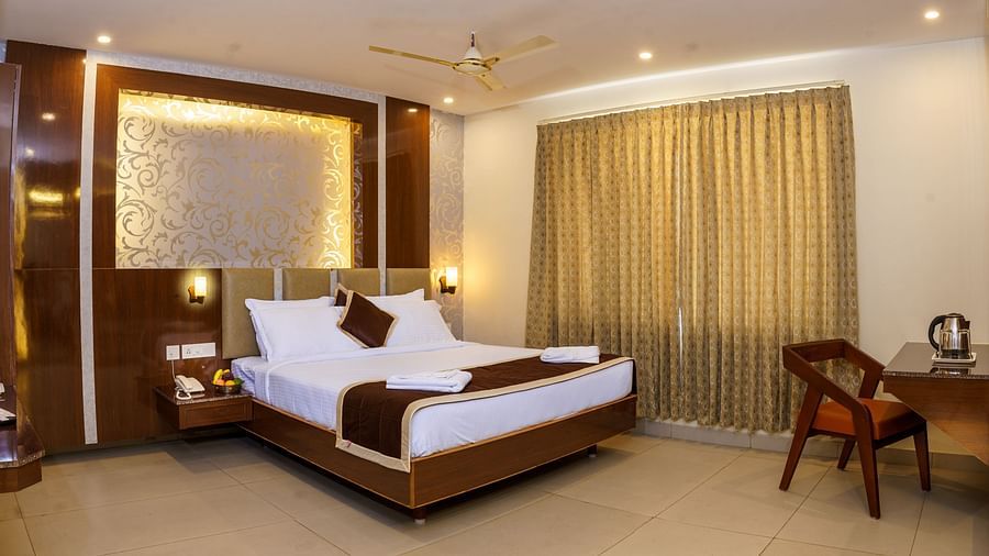 Wide angle view of deluxe room with bed, study area and dressing table at Wyt Hotels, Rameswaram