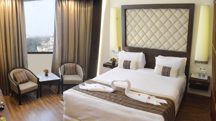 A cosy bedroom with a stylish headboard, soft lighting, and modern decor in a luxury hotel in Lucknow - Clarks Avadh, Lucknow.