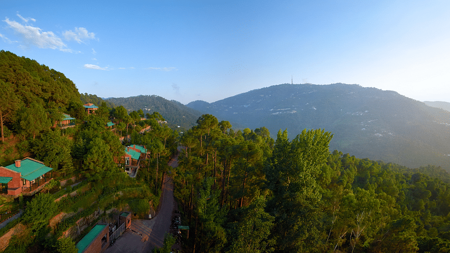 a drone shot of a facade of the hotel with the sun coming up over the mountains - Baikunth Resort, Kasauli