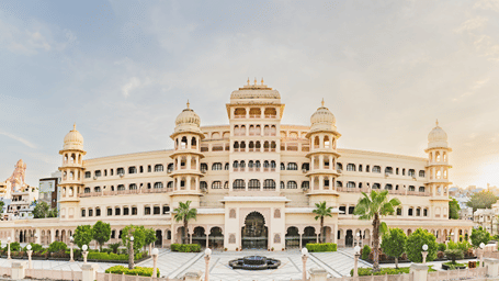The grand Rajasthani palace-style Shri Vallab Vilas Lords Plaza property, featuring ornate jharokhas, domes, and a stone courtyard with a central fountain.