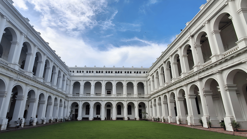 Historic Indian Museum building with arched corridors surrounding an open courtyard in Kolkata.