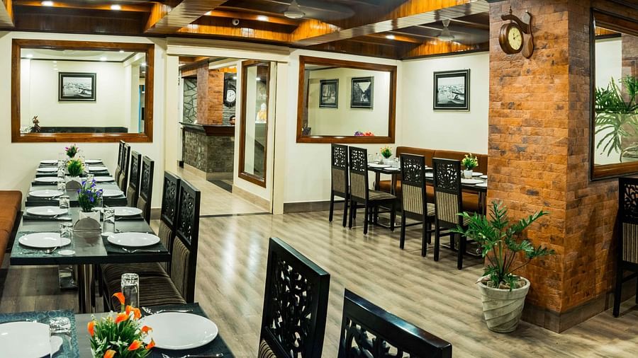 An image of a restaurant with seating arrangement and tables laid out with plates and cutlery - Ecotel Tin Tin, Bijanbari