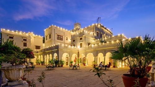 Facade with lights on and chairs and table in the foreground - The Baradari Palace