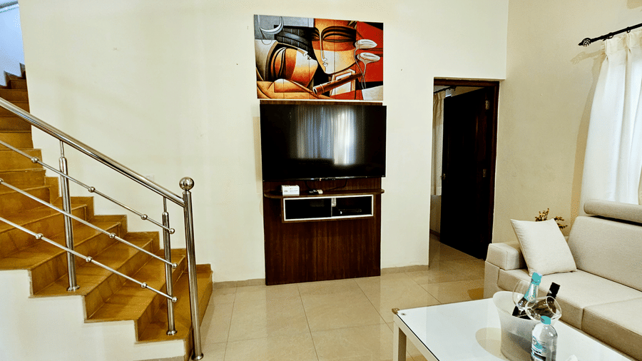 A huge wall-mounted television along with a painted canvas hung above it in the living room of Amara Villa, Nagoa.