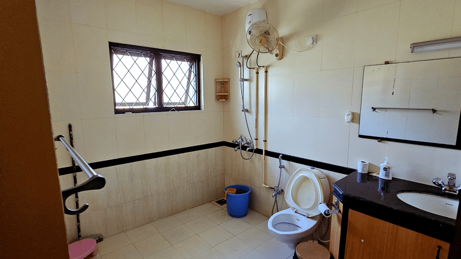 A spacious bathroom featuring a vanity area along with a commode and a shower head at Amara Villa, Nagoa.