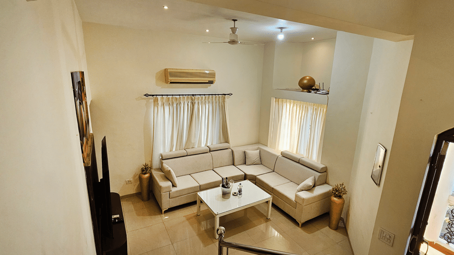 A wide-angle shot of the living room featuring the seating area and the open main door in the corner at Amara Villa, Nagoa.