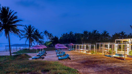 A view of Benaulim Beach after sunset with lounge chairs and cabana set up on the shoreline at Blue Iris Restaurant at Azaya Beach Resort, Goa.