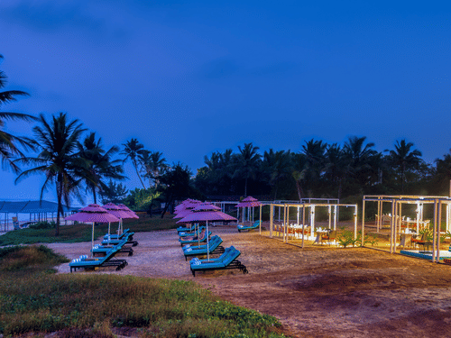 A view of Benaulim Beach after sunset with lounge chairs and cabana set up on the shoreline at Blue Iris Restaurant at Azaya Beach Resort, Goa.