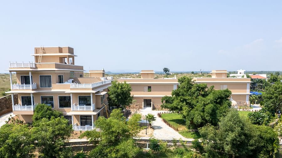 An aerial shot a facade in between lush greenery seen on a sunny day - Rajbagh Wellness, Udaipur.