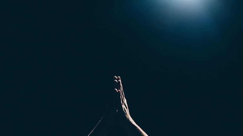 folded hands of a person in a praying gesture with a black baakground
