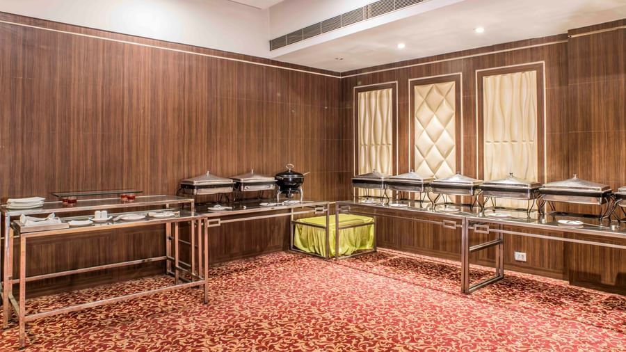 A buffet area with serving dishes in a room with wood-paneled walls at The Citi Residenci Hotel, Durgapur.