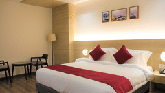 Premium King size bed with comfortable side chairs and table at Pride Biznotel Haldwani