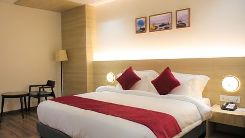 Premium King size bed with comfortable side chairs and table at Pride Biznotel Haldwani