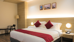 Premium King size bed with comfortable side chairs and table at Pride Biznotel Haldwani