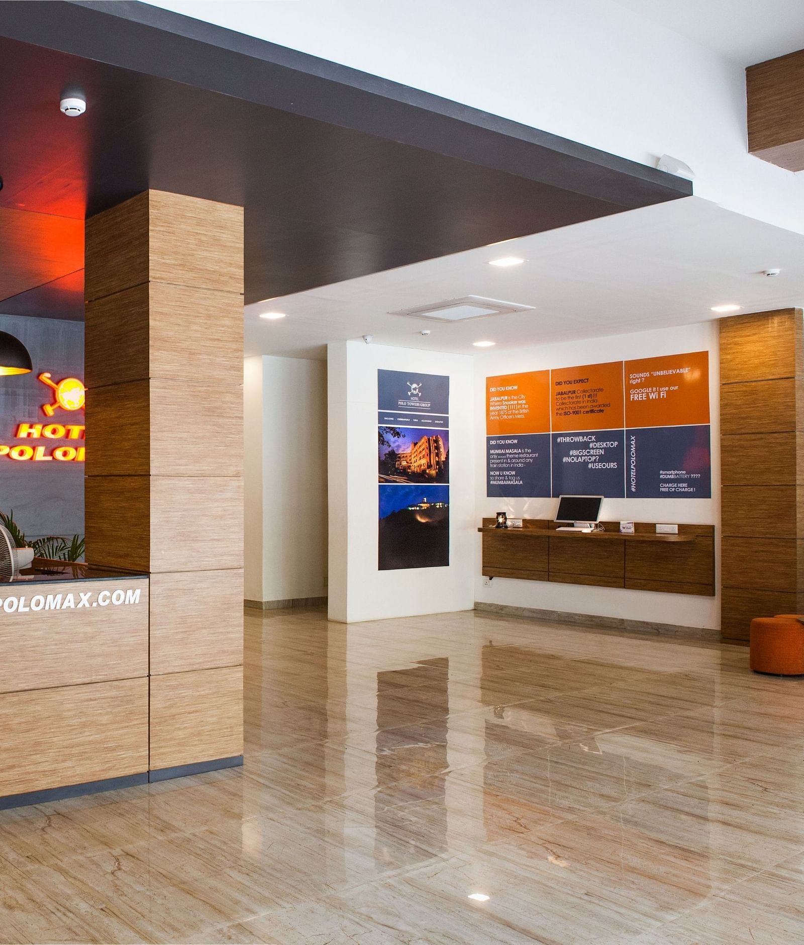 The lobby area featuring a polished floor, columns, and a wall display with screens at Max Hotel Jabalpur.