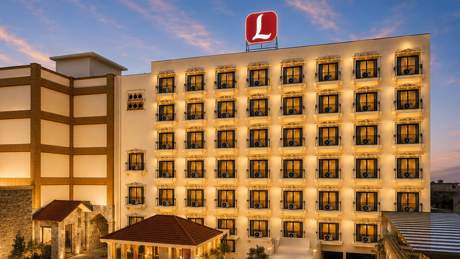 Exterior view of Diamond Palace Lords Plaza Nepalgunj at dusk featuring a grand multi-story building illuminated with warm golden window lights, blue decorative balconies, and a red rooftop logo against a soft evening sky.