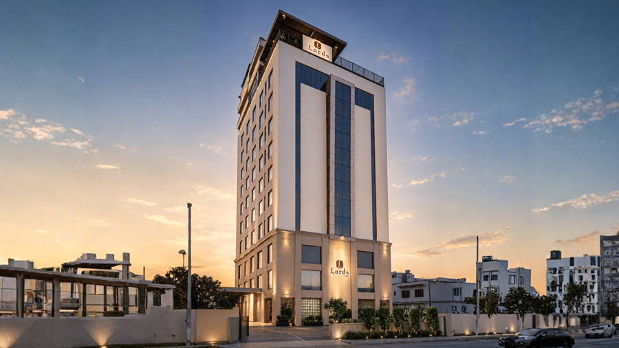 Exterior view of Libra Lords Inn Jaipur showcasing a multi-story modern hotel building illuminated at dusk against a sunset sky.
