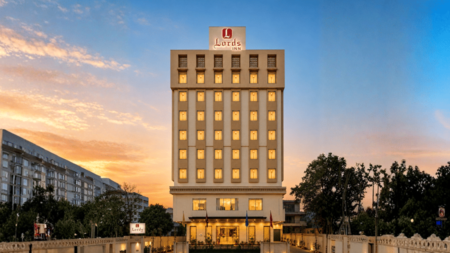 Exterior view of Lords Inn Jodhpur showcasing a tall multi-story hotel building with glowing windows during sunset.