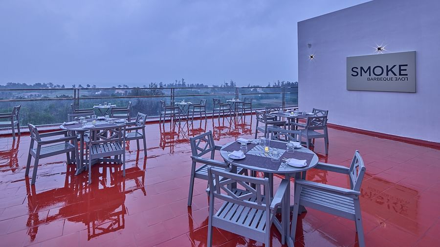 tables and chairs in front of a board that says 'smoke barbeque love' at our rooftop restaurant in Mahabalipuram - Grand Continent, Mahabalipuram
