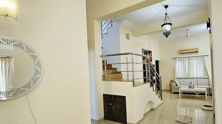 A brightly-lit interior of the villa featuring a staircase leading to the upper level with a living area in the front at Amara Villa, Nagoa.