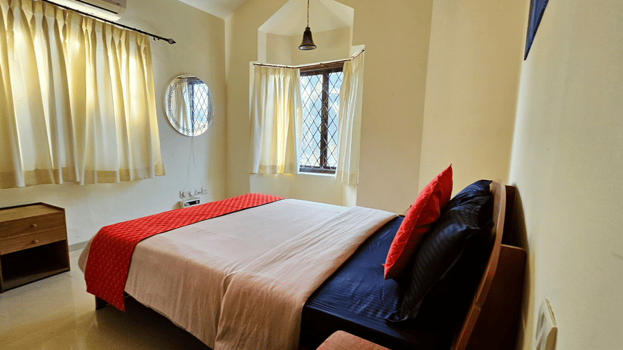 A wide-angle shot of a bedroom featuring a double bed facing the windows covered with cream-coloured drapes at Amara Villa, Nagoa.