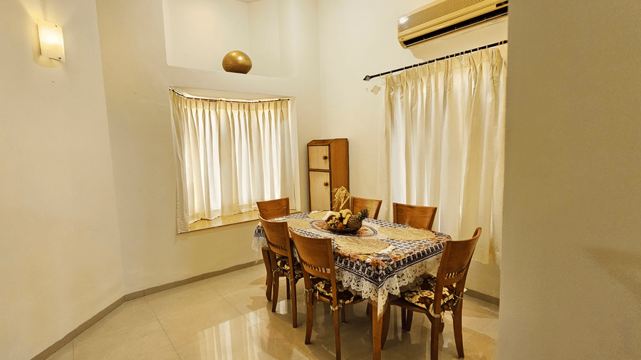 The dining area featuring 6 chairs surrounding the dining table along with a wall-mounted split A/C at Amara Villa, Nagoa.