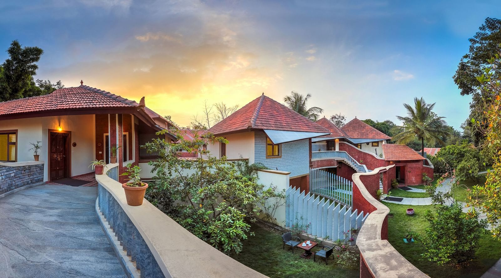 A facade image of a perperty showcasig two different buildings amidst the trees - Hoysala Village Resort, Hassan