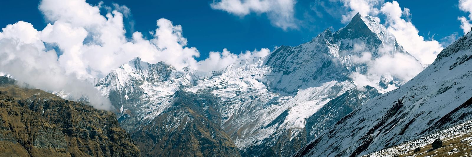 A mountain range, possibly the Himalayas, with snow-capped peaks and some cloud cover.