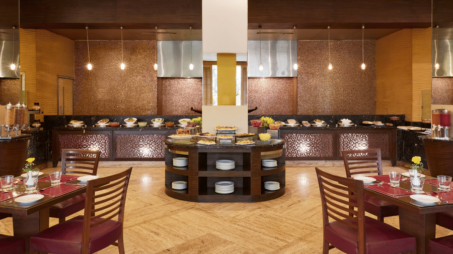 A restaurant dining hall with rows of tables and chairs arranged around a central buffet counter at The Retreat Hotel & Convention Centre.