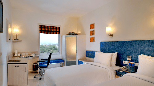 Superior twin Room at Hometel Chandigarh featuring twin beds, bedside table, and a work station.