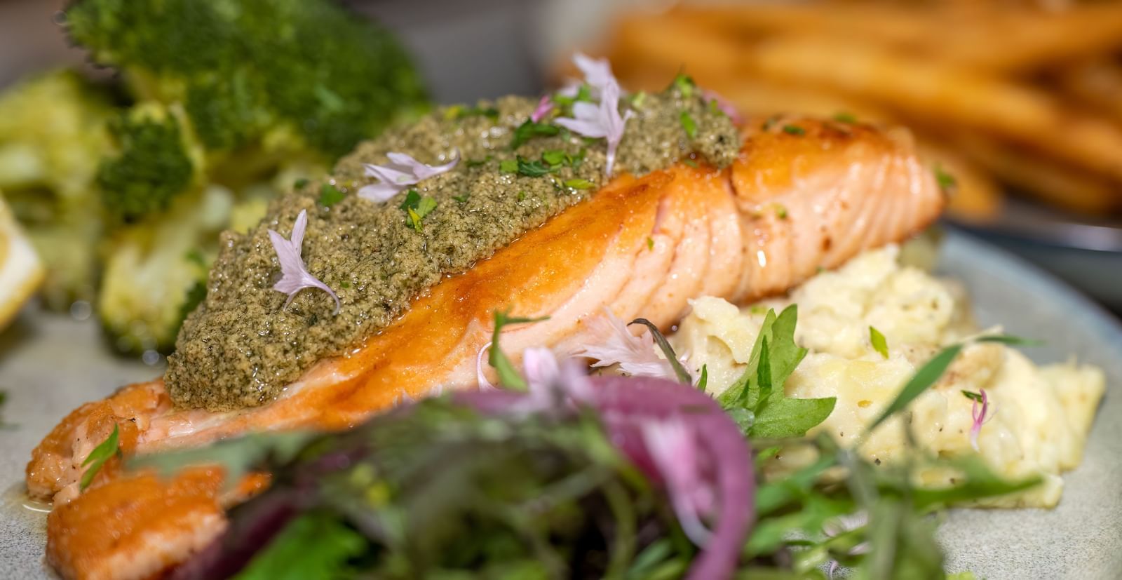 Grilled salmon fillet served with mashed potatoes, broccoli, and fresh greens at Narrow Gauge Inn.