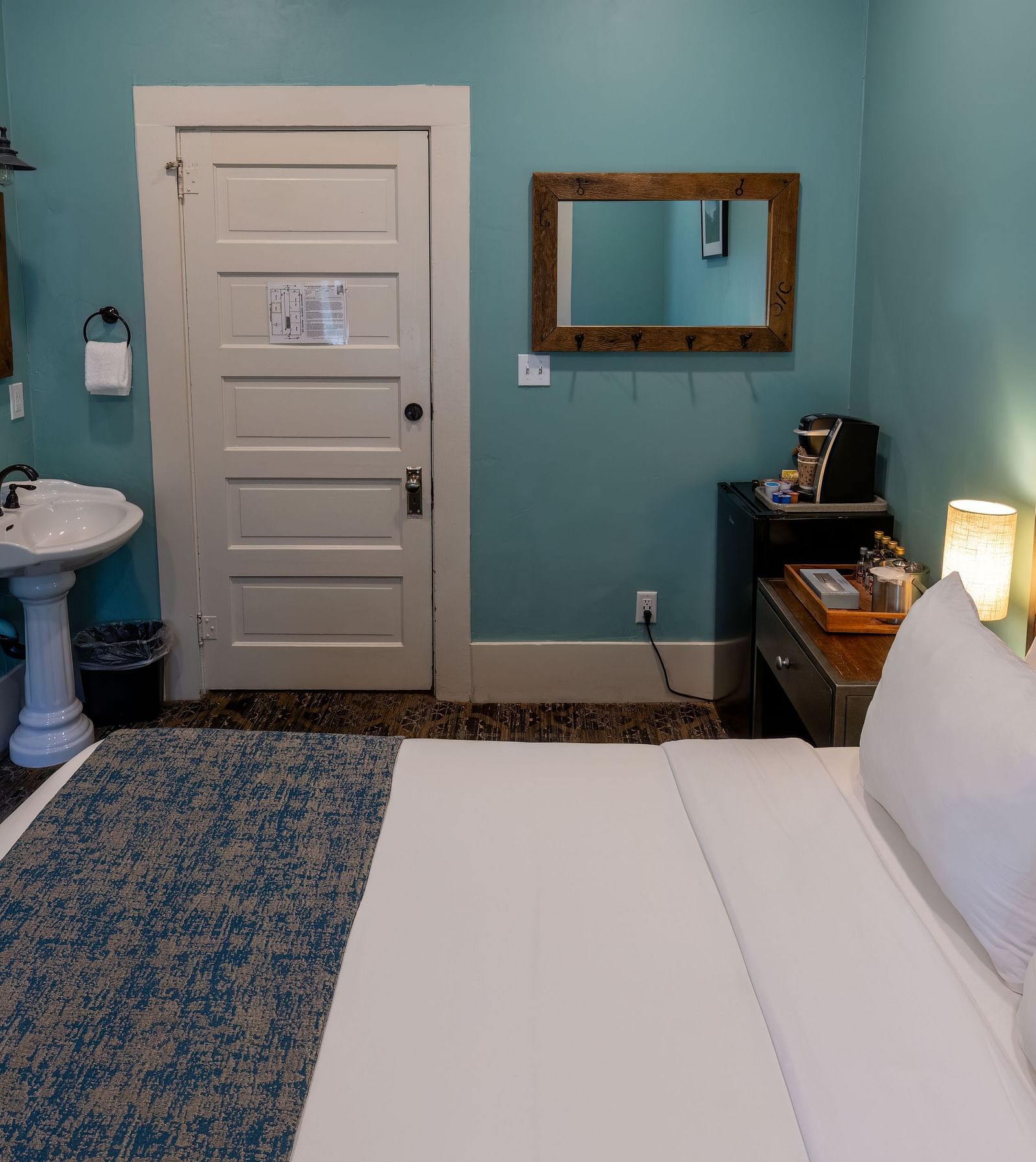 Comfortable guest room with twin beds, ensuite bathroom and teal walls at The Groveland Hotel.