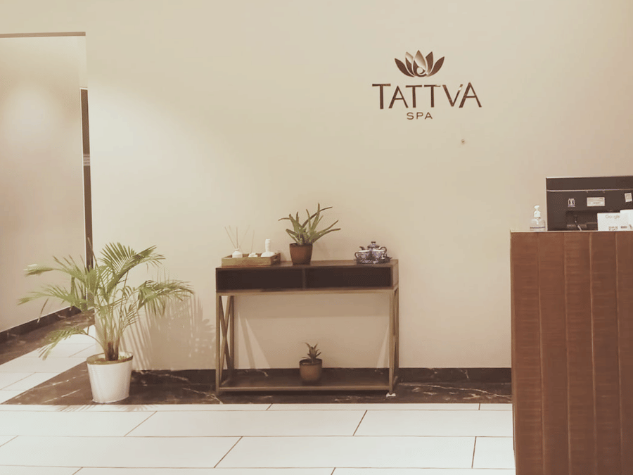 The signage of tattva spa on the wall with the reception desk below at  Polo Hotel Agartala