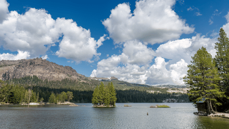 Panoramic view of Silver Lake with distant mountains and forested shores under a bright sky.
