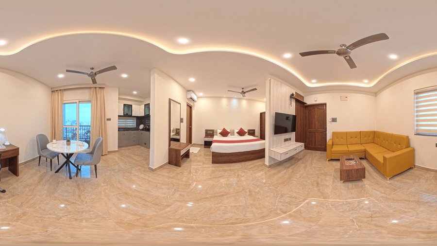 A 360-degree panorama shows a room with a bed, yellow sofa, and desk under ceiling lights at Elysium Studio Suites, Madhapur.