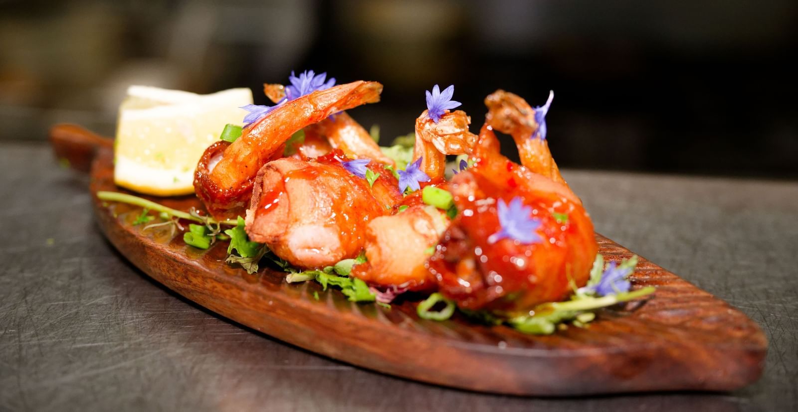 Grilled shrimp served on a wooden platter with salad and lemon at Narrow Gauge Inn.