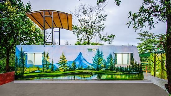 Eco Pod room in a natural setting with an exterior painting of a river, grass, trees, mountains, and sky