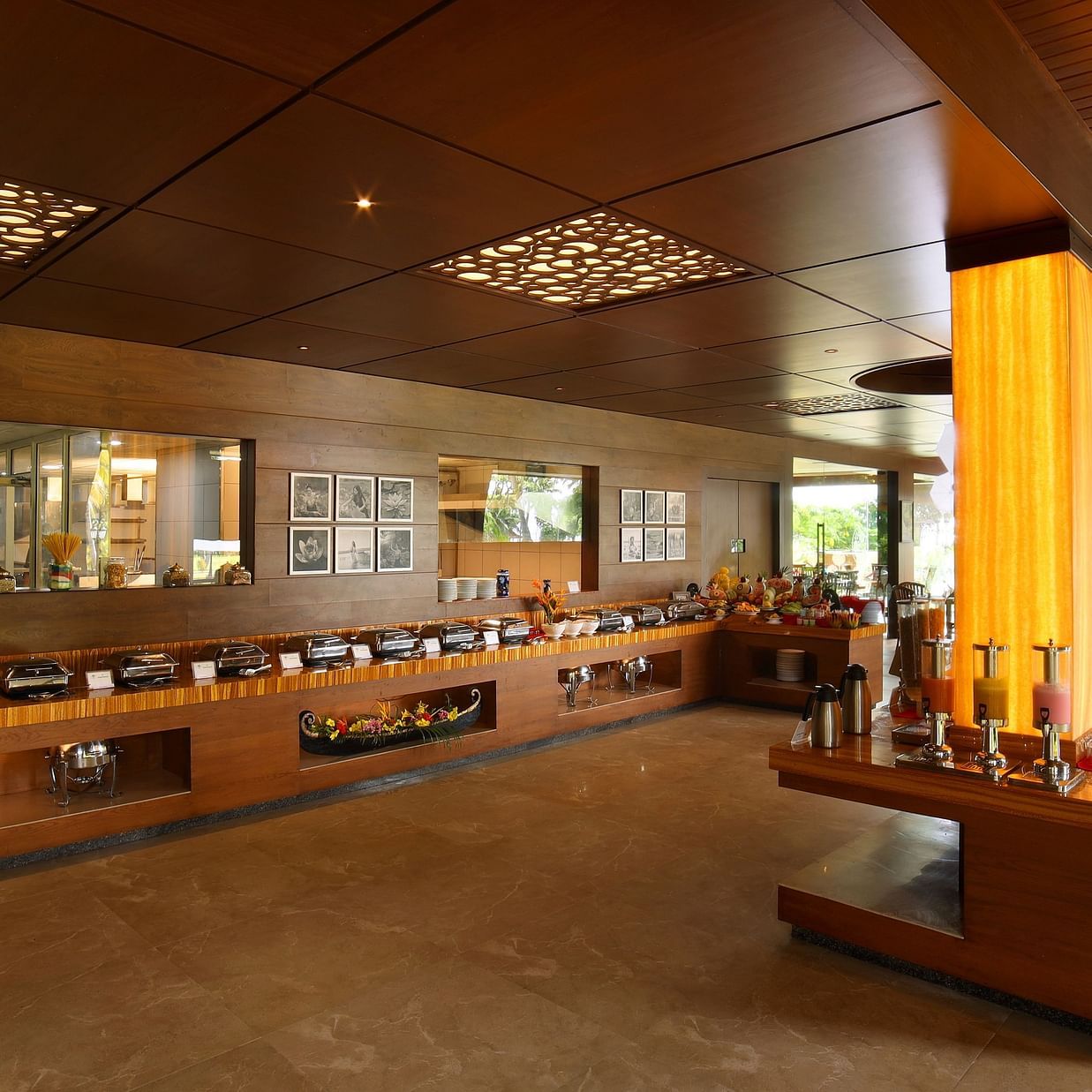 Aambal Restaurant at Uday Backwater Resort, with tables set on one side overlooking the outdoors and buffet counters on the other